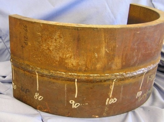 The picture looks up at a wall made of riveted coper plating. The wall is not flat, but has wave like projections.